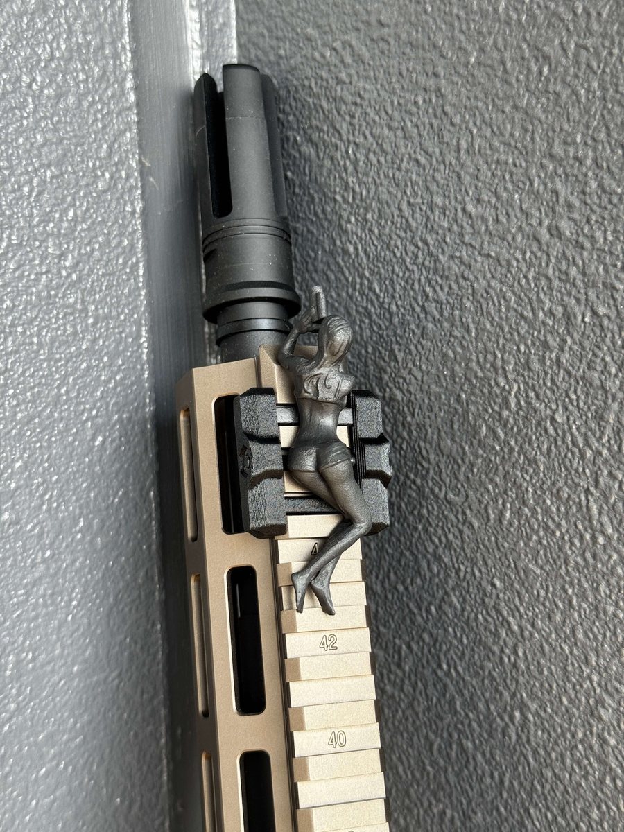 Spotter G figure mounted near the muzzle end of a rifle's rail