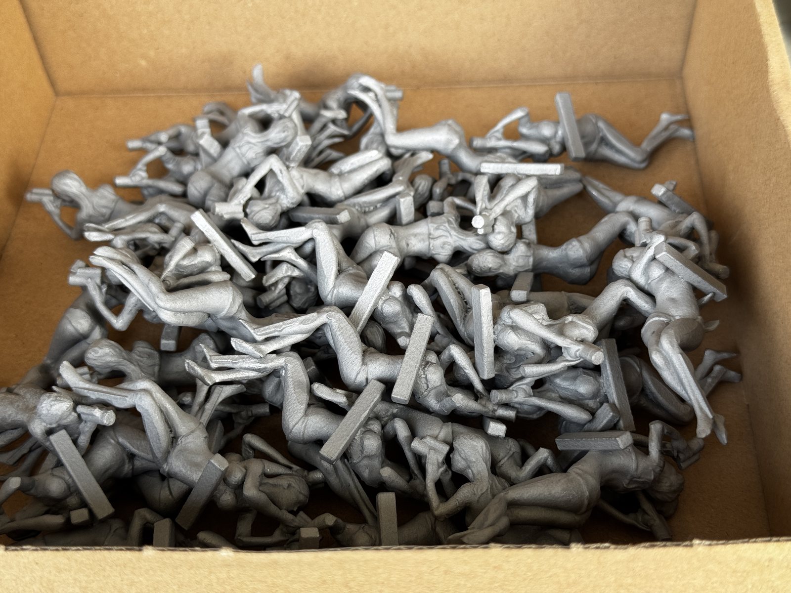 A production batch of stainless-steel Spotter G figures fresh from metal 3D printing